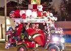 Santa and helpers ride a festively decorated golf cart stacked with gifts during the Christmas parade. Santa and helpers ride a festively decorated golf cart stacked with gifts during the Christmas parade.
