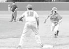 Hughes Springs’ Andrew Gaul dives back to first on an attempted pickoff as Daingerfield’s Austin Fomby covers the base. The Mustangs would go on to win the matchup, 8-0. Article Image Alt Text